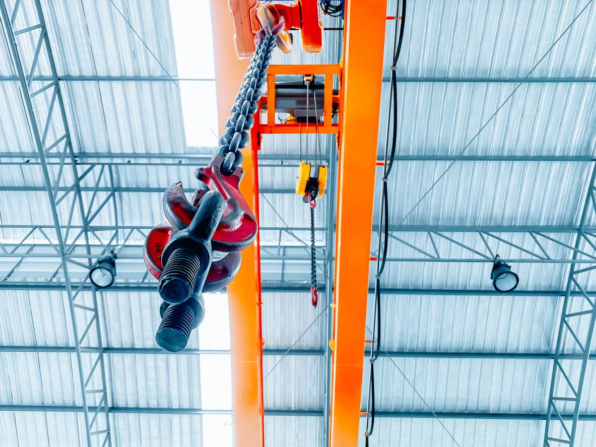 Overhead crane inside factory building, industrial background.
